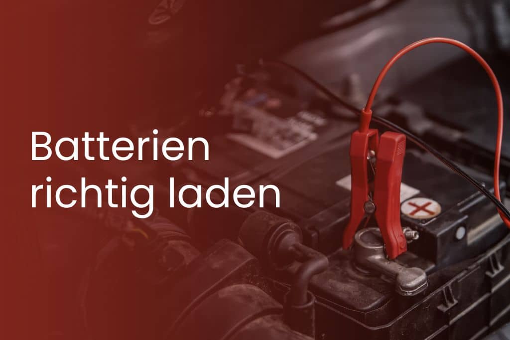 Close-up of a car battery with red charging clamps connected, with the words "Charge batteries correctly" on a red background next to it.