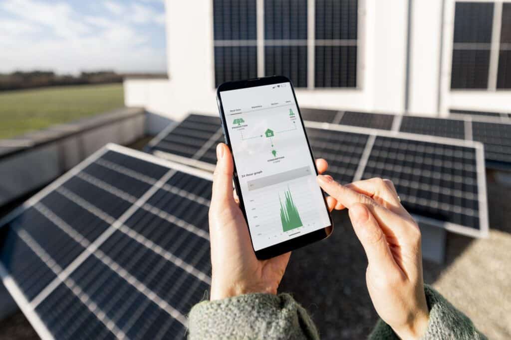 Woman monitors the energy production of the solar system with her mobile phone. Close-up of the screen with the programme running.