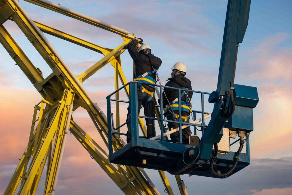 Two construction workers working on a lifting platform.