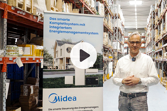 Midea complete system with energy manager presented in the warehouse; person standing next to banner with image of house and system. Play button in the centre of the picture.